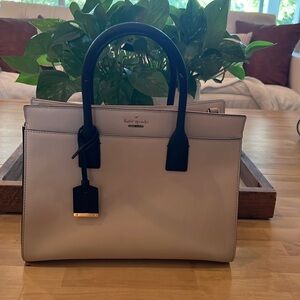 Light pink Kate Spade bag with black handles.